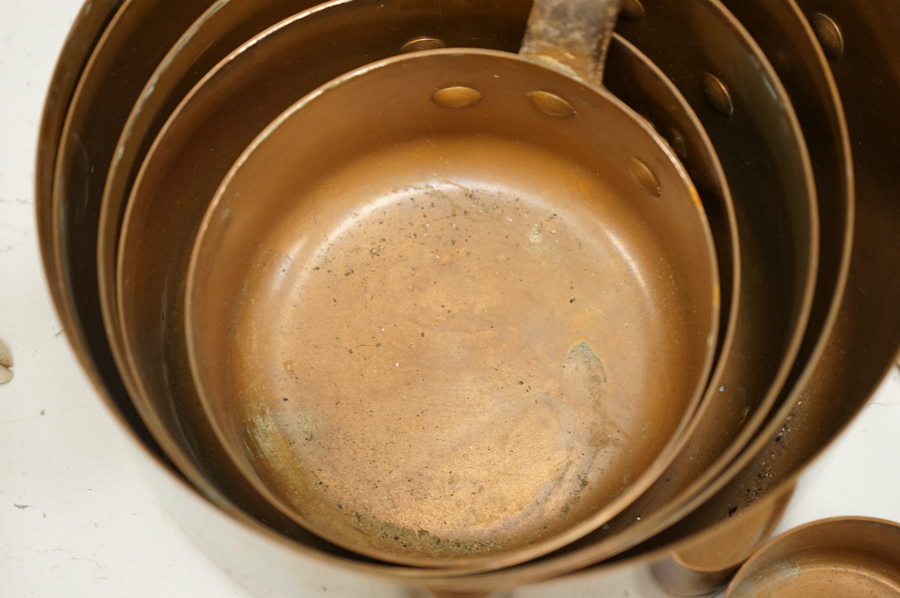 A graduated set of copper saucepans, largest 20.5cm diameter, smallest 6.5cm